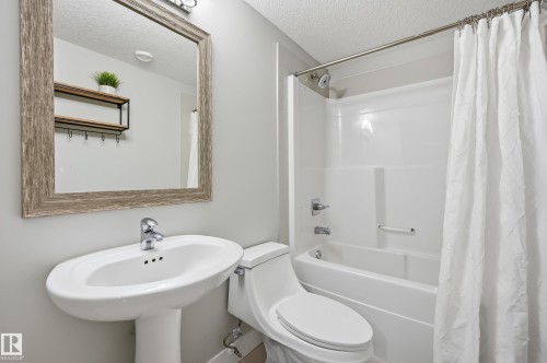 Bathroom with a textured ceiling and shower / bathtub combination with curtain - 30 Willow Link, Fort Saskatchewan, AB - Indoor Photo Showing Bathroom