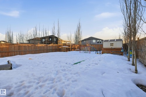 Yard covered in snow with a fenced backyard, a residential view, and a deck - 30 Willow Link, Fort Saskatchewan, AB - Outdoor