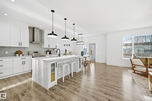 Kitchen featuring a breakfast bar area, hanging light fixtures, white cabinetry, a center island with sink, and electric range - 30 Willow Link, Fort Saskatchewan, AB - Indoor Photo Showing Kitchen With Upgraded Kitchen