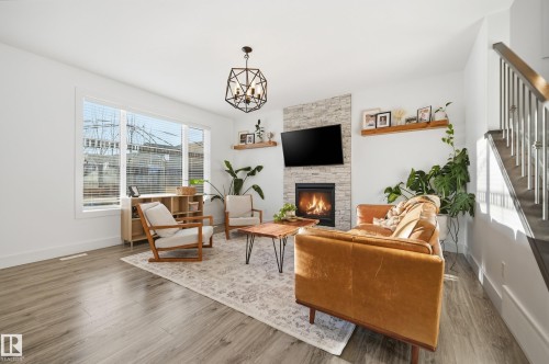Living room with suspended lighting, wood finished floors, and a stone fireplace - 30 Willow Link, Fort Saskatchewan, AB - Indoor Photo Showing Living Room With Fireplace