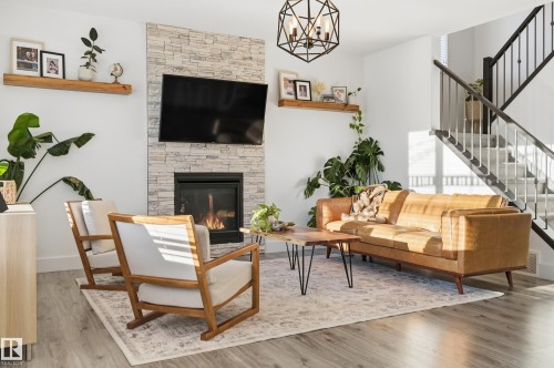 Living room featuring suspended lighting, a fireplace, wood finished floors, and plenty of natural light - 30 Willow Link, Fort Saskatchewan, AB - Indoor Photo Showing Living Room With Fireplace