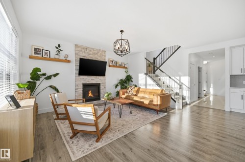 Living area with wood finished floors, a chandelier, and a fireplace - 30 Willow Link, Fort Saskatchewan, AB - Indoor Photo Showing Living Room With Fireplace