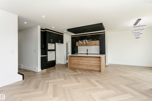 Kitchen featuring a center island with sink, two tone color scheme, parquet floors, recessed lighting, and modern cabinets - 3248 Pelerin Crescent, Beaumont, AB - Indoor
