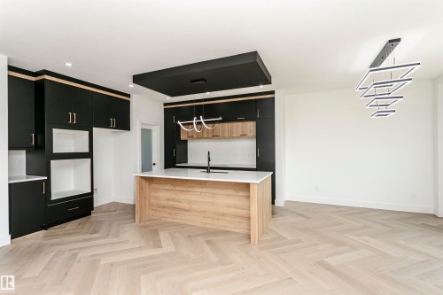 Dual tone kitchen featuring two tone color scheme, a kitchen island with sink, light stone countertops, parquet floors, and suspended lighting - 3248 Pelerin Crescent, Beaumont, AB - Indoor Photo Showing Other Room