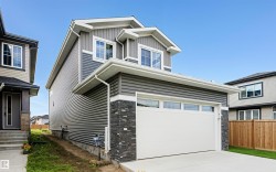 View of front of home with stone siding, board and batten siding, driveway, and a garage - 