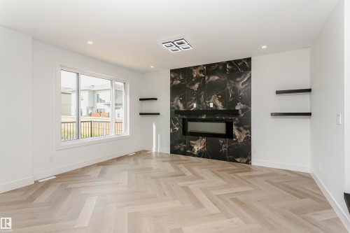Unfurnished living room featuring parquet floors, a high end fireplace, and recessed lighting - 3248 Pelerin Crescent, Beaumont, AB - Indoor Photo Showing Other Room With Fireplace