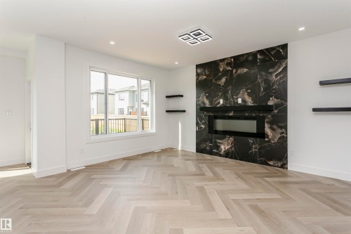 Unfurnished living room with a premium fireplace, parquet floors, and recessed lighting - 3248 Pelerin Crescent, Beaumont, AB - Indoor With Fireplace