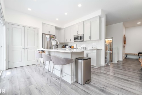 Kitchen with a kitchen island with sink, light wood finished floors, a breakfast bar area, stainless steel appliances, and recessed lighting - 2330 Kelly Circle, Edmonton, AB - Indoor Photo Showing Kitchen With Upgraded Kitchen