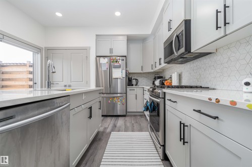 Kitchen featuring stainless steel appliances, light stone counters, light wood-type flooring, recessed lighting, and decorative backsplash - 2330 Kelly Circle, Edmonton, AB - Indoor Photo Showing Kitchen With Upgraded Kitchen