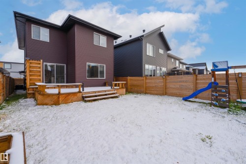 Snow covered back of property with a playground, a fenced backyard, and a deck - 2330 Kelly Circle, Edmonton, AB - Outdoor With Deck Patio Veranda With Exterior
