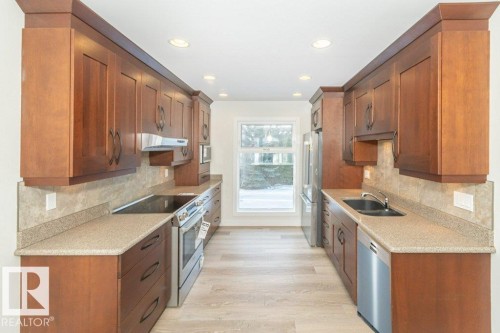 Kitchen with stainless steel appliances, light wood-style flooring, light stone counters, wood finish cabinets, and recessed lighting - 5720 109A Street Nw, Edmonton, AB - Indoor Photo Showing Kitchen With Double Sink