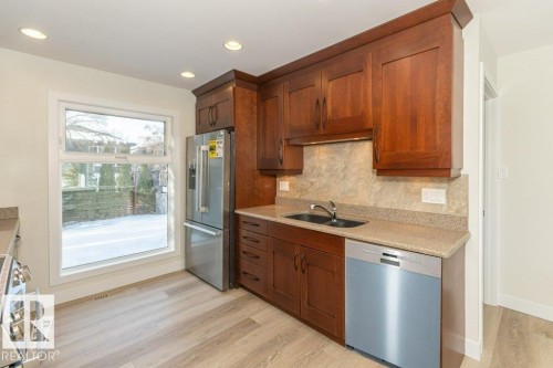 Kitchen featuring stainless steel appliances, light wood finished floors, backsplash, light stone countertops, and wood finish cabinetry - 5720 109A Street Nw, Edmonton, AB - Indoor Photo Showing Kitchen With Double Sink