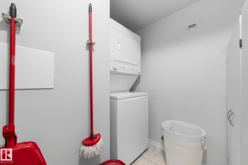 Laundry room with stacked washer / dryer and light tile patterned flooring - 301 10118 106 Avenue, Edmonton, AB - Indoor Photo Showing Laundry Room