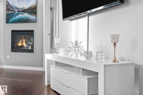Detailed view of a glass covered fireplace and wood finished floors - 301 10118 106 Avenue, Edmonton, AB - Indoor Photo Showing Other Room