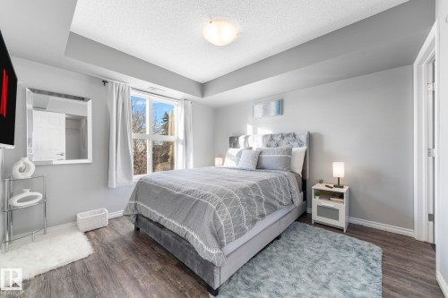 Bedroom with dark wood-style floors and a textured ceiling - 301 10118 106 Avenue, Edmonton, AB - Indoor Photo Showing Bedroom