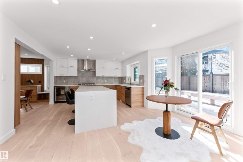 Two tone kitchen featuring modern cabinets, dual tone cabinetry, backsplash, a kitchen bar, and light wood finished floors - 607 Butterworth Wynd, Edmonton, AB - Indoor