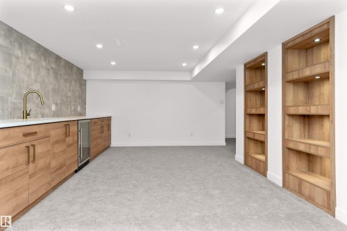 Indoor wet bar with built in shelves, light carpet, recessed lighting, wine cooler, and wood finish cabinets - 607 Butterworth Wynd, Edmonton, AB - Indoor Photo Showing Other Room