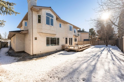 Back of property featuring a fenced backyard, a wooden deck, stucco siding, and a chimney - 607 Butterworth Wynd, Edmonton, AB - Outdoor With Exterior