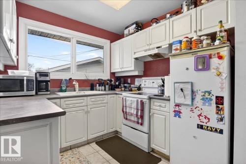Kitchen with white appliances, white cabinetry, light tile patterned floors, and dark countertops - 13320 123 Street, Edmonton, AB - Indoor Photo Showing Kitchen