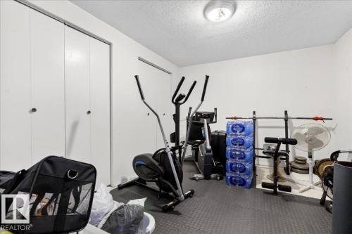 Exercise room with a textured ceiling and rubber floors - 13320 123 Street, Edmonton, AB - Indoor Photo Showing Gym Room