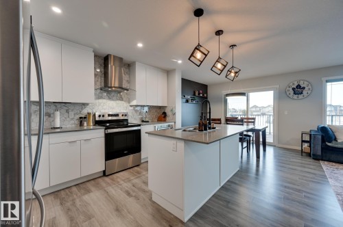Kitchen with stainless steel appliances, white cabinetry, a kitchen island with sink, and modern cabinets - 4 Caledon Crescent, Spruce Grove, AB - Indoor Photo Showing Kitchen With Stainless Steel Kitchen With Upgraded Kitchen