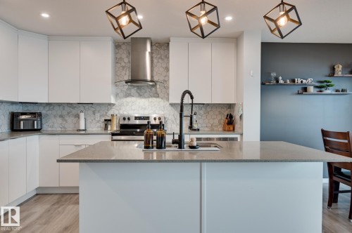 Kitchen featuring modern cabinets, light wood-style flooring, and white cabinets - 4 Caledon Crescent, Spruce Grove, AB - Indoor Photo Showing Kitchen With Double Sink With Upgraded Kitchen