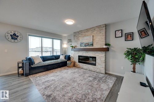 Living area featuring dark wood-style floors and a stone fireplace - 4 Caledon Crescent, Spruce Grove, AB - Indoor Photo Showing Living Room With Fireplace