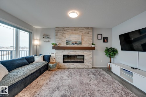 Living area featuring wood finished floors and a stone fireplace - 4 Caledon Crescent, Spruce Grove, AB - Indoor Photo Showing Living Room With Fireplace