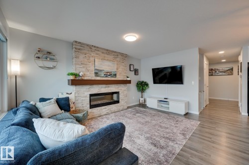 Living area featuring a stone fireplace, wood finished floors, and recessed lighting - 4 Caledon Crescent, Spruce Grove, AB - Indoor Photo Showing Living Room With Fireplace