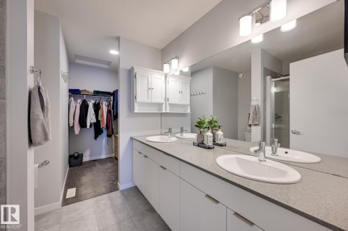 Full bath featuring a spacious closet, a stall shower, double vanity, light colored carpet, and light tile patterned flooring - 4 Caledon Crescent, Spruce Grove, AB - Indoor Photo Showing Bathroom