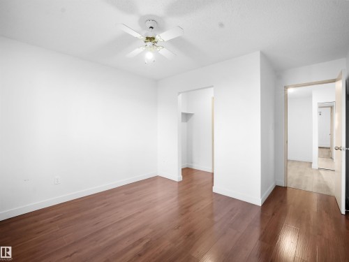 Unfurnished bedroom with dark wood-style floors, a ceiling fan, and a walk in closet - 108 5065 31 Avenue, Edmonton, AB - Indoor Photo Showing Other Room