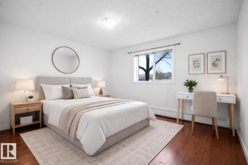 Bedroom with baseboard heating, dark wood-style floors, and a textured ceiling - 108 5065 31 Avenue, Edmonton, AB - Indoor Photo Showing Bedroom