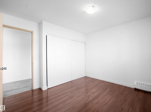 Unfurnished bedroom with dark wood-style floors, a textured ceiling, and a closet - 108 5065 31 Avenue, Edmonton, AB - Indoor Photo Showing Other Room