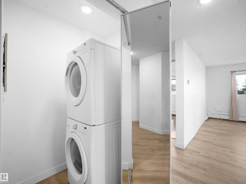 Laundry area featuring stacked washer / drying machine, light wood-style flooring, a textured ceiling, baseboard heating, and recessed lighting - 108 5065 31 Avenue, Edmonton, AB - Indoor Photo Showing Laundry Room