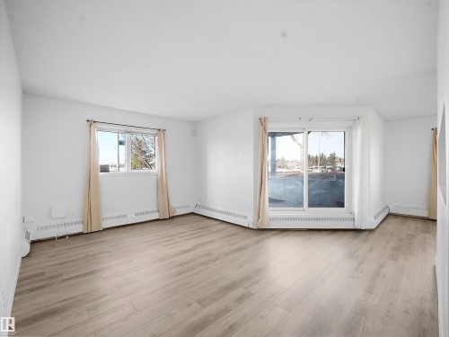 Spare room featuring light wood-type flooring, baseboard heating, and a baseboard radiator - 108 5065 31 Avenue, Edmonton, AB - Indoor Photo Showing Other Room
