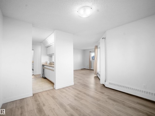Unfurnished room featuring light wood finished floors, a textured ceiling, and a baseboard heating unit - 108 5065 31 Avenue, Edmonton, AB - Indoor Photo Showing Other Room