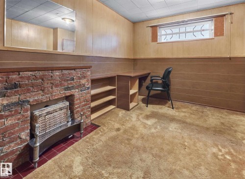 Unfurnished office featuring wooden walls, light colored carpet, wainscoting, and a brick fireplace - 11127 71 Avenue, Edmonton, AB - Indoor Photo Showing Other Room With Fireplace