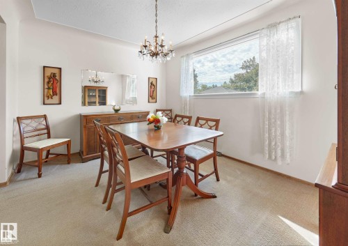 Dining space featuring hanging lights, light colored carpet, and a textured ceiling - 11127 71 Avenue, Edmonton, AB - Indoor Photo Showing Dining Room