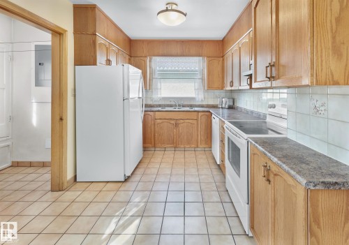 Kitchen with white appliances, backsplash, electric panel, light tile patterned floors, and dark countertops - 11127 71 Avenue, Edmonton, AB - Indoor Photo Showing Kitchen With Double Sink