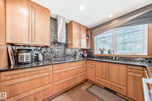 Kitchen with dark stone countertops, light wood finish cabinets, recessed lighting, open shelves, and backsplash - 4 Harriott Court, St. Albert, AB - Indoor Photo Showing Kitchen