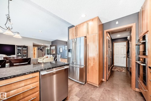 Kitchen featuring light wood finish cabinets, stainless steel appliances, decorative light fixtures, open floor plan, and dark stone countertops - 4 Harriott Court, St. Albert, AB - Indoor Photo Showing Kitchen With Stainless Steel Kitchen