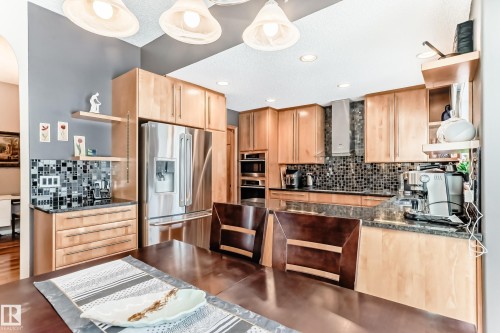 Kitchen with open shelves, light wood finish cabinets, stainless steel appliances, dark stone countertops, and a textured ceiling - 4 Harriott Court, St. Albert, AB - Indoor Photo Showing Kitchen With Stainless Steel Kitchen