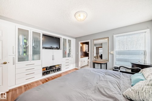 Bedroom featuring a textured ceiling, light wood finished floors, and connected bathroom - 4 Harriott Court, St. Albert, AB - Indoor Photo Showing Bedroom
