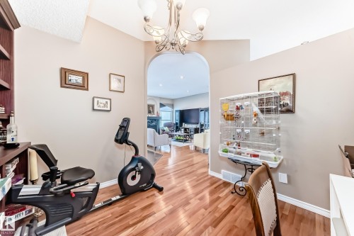 Workout room with arched walkways, light wood-style flooring, and a chandelier - 4 Harriott Court, St. Albert, AB - Indoor Photo Showing Gym Room