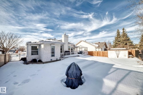 Snow covered rear of property with a wooden deck, a fenced backyard, and a chimney - 4 Harriott Court, St. Albert, AB - Outdoor