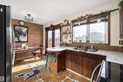 Kitchen featuring freestanding refrigerator, brick wall, electric range, light countertops, and french doors - 