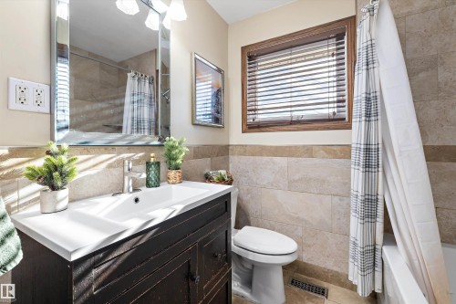 Bathroom with vanity, shower / tub combo, light tile patterned floors, tile walls, and wainscoting - 5703 143 Avenue, Edmonton, AB - Indoor Photo Showing Bathroom