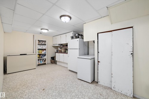 Kitchen with white cabinets, freestanding refrigerator, a drop ceiling, light countertops, and light floors - 5703 143 Avenue, Edmonton, AB - Indoor