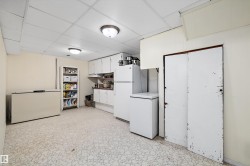 Kitchen with white cabinets, freestanding refrigerator, a drop ceiling, light countertops, and light floors - 
