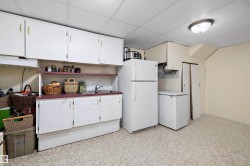 Kitchen with freestanding refrigerator, open shelves, white cabinets, light floors, and a paneled ceiling - 